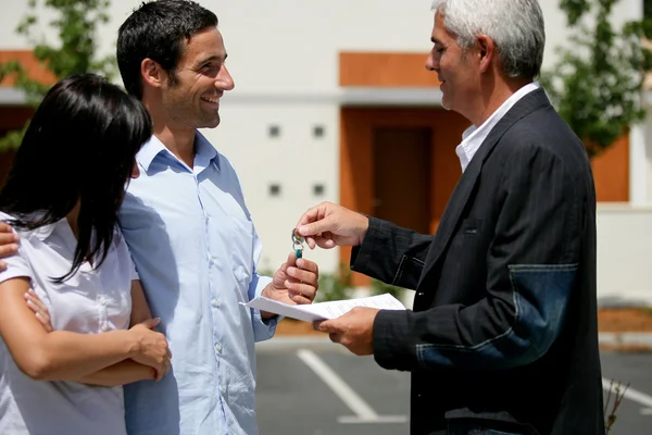 A happy couple accept a key to their new home from their new landlord.